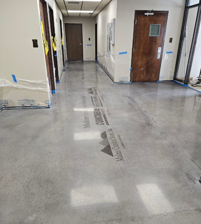 A hallway with a shiny concrete floor and a wooden door.