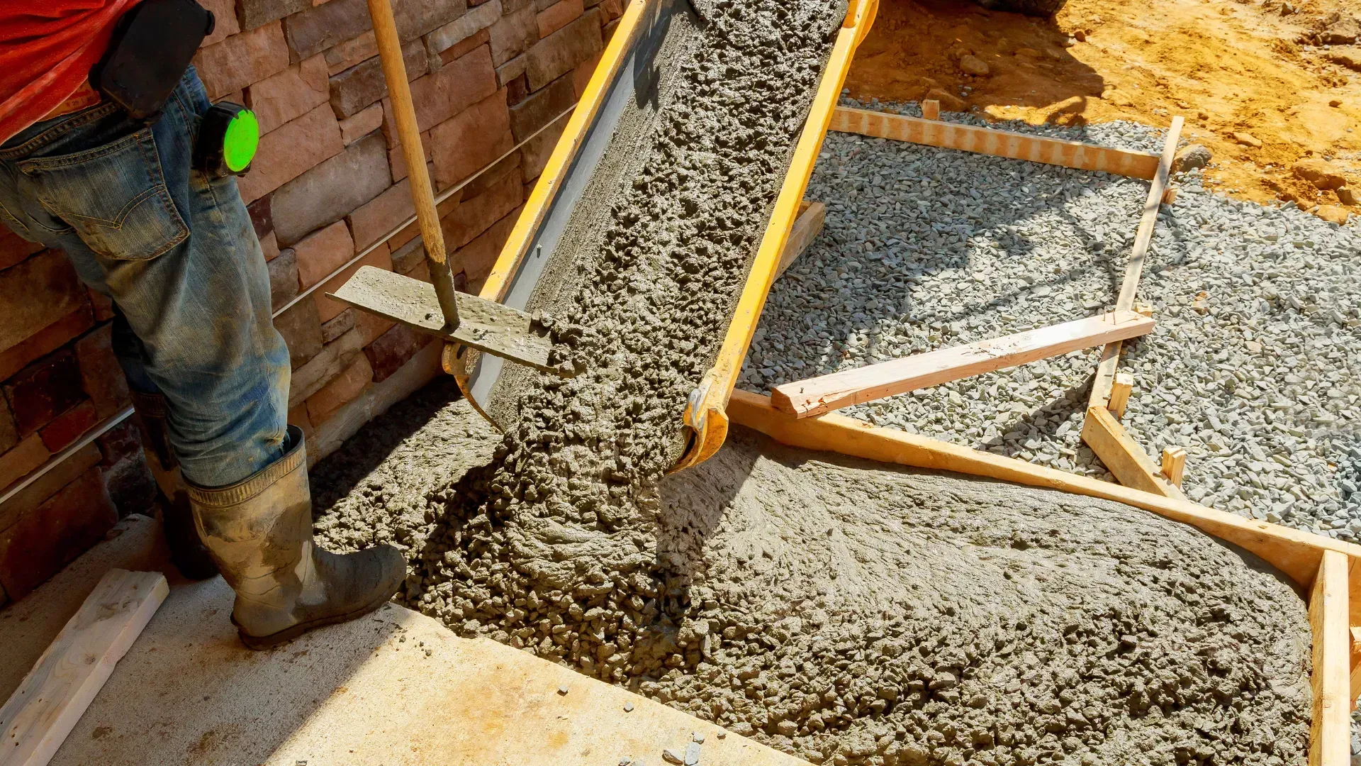 A man is pouring concrete into a concrete form.