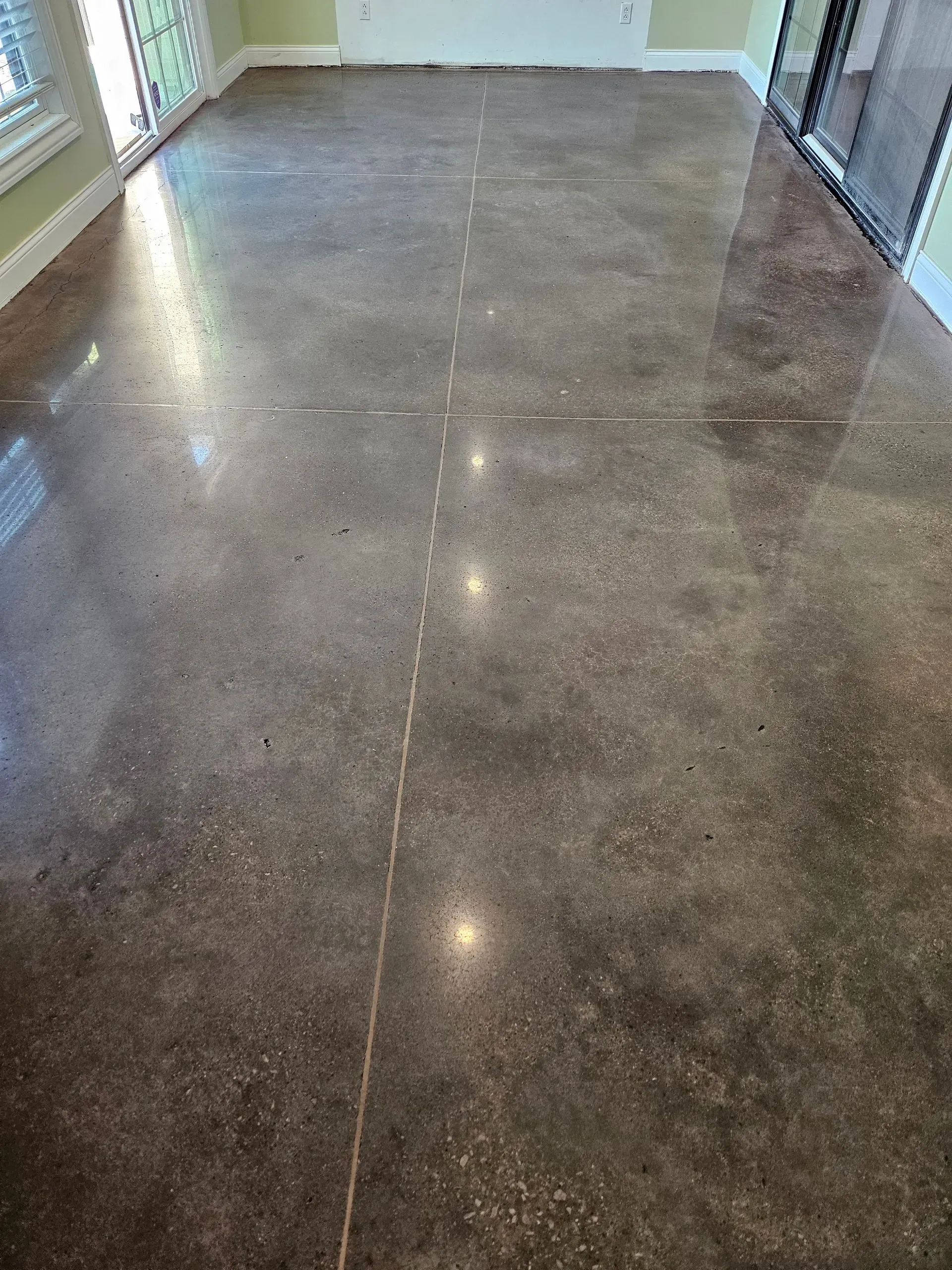 A shiny concrete floor in a living room with a sliding glass door.
