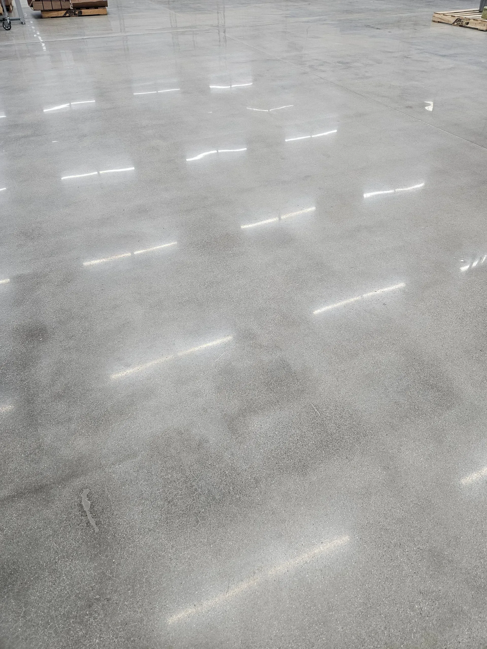 A large warehouse with a shiny concrete floor and lots of lights shining on it.