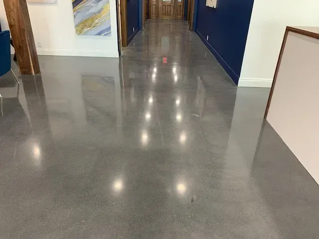 A hallway with a shiny concrete floor and a painting on the wall.