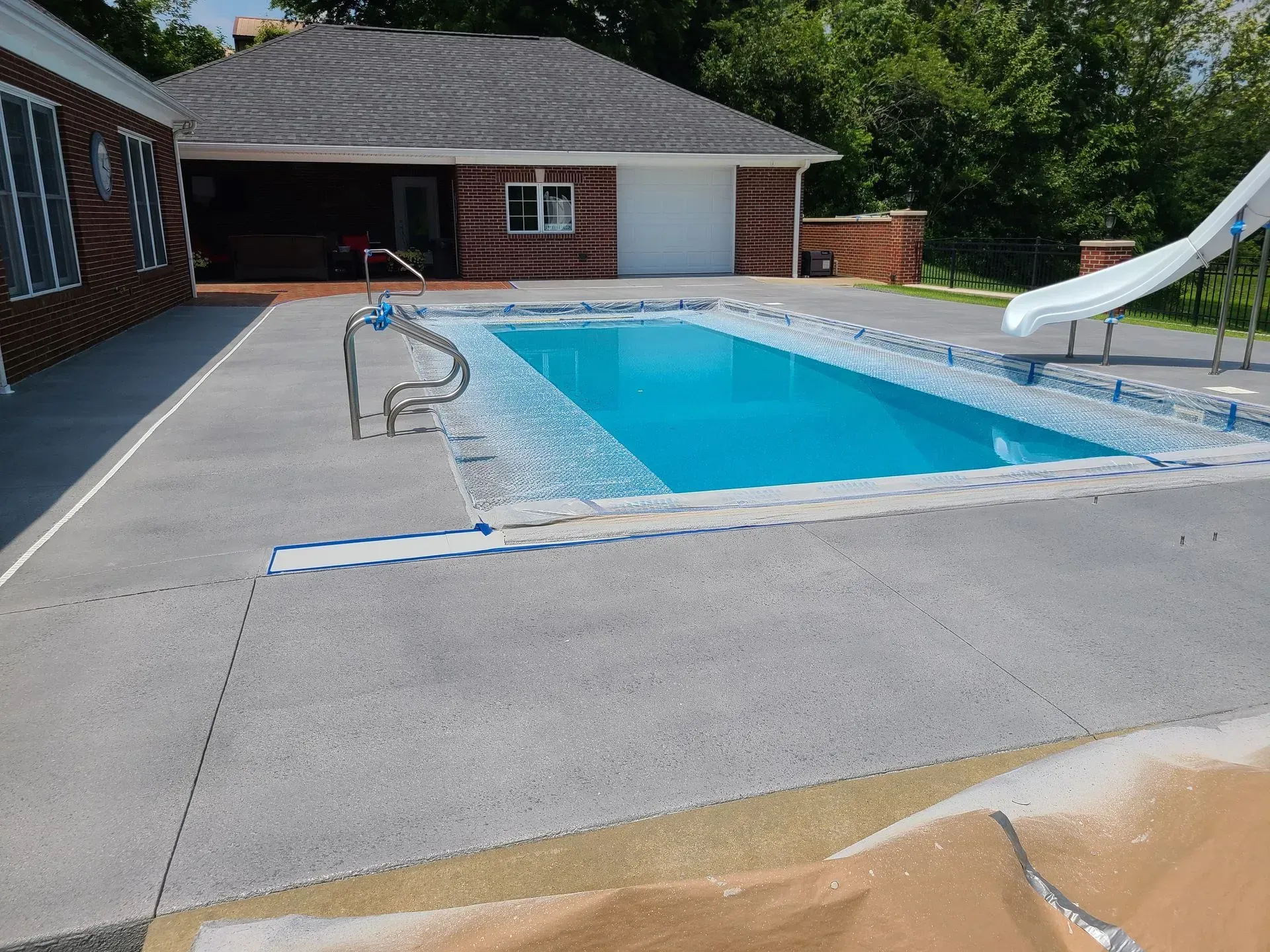 A large swimming pool with a slide in front of a house
