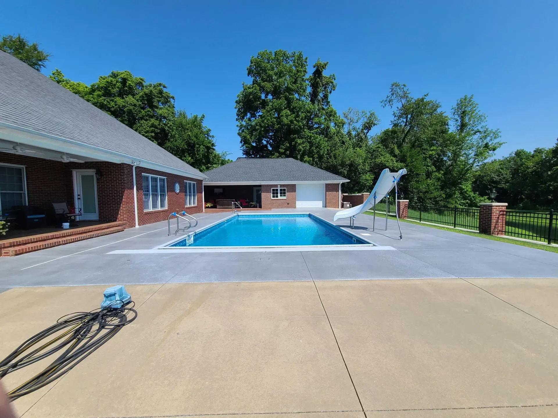A large swimming pool with a slide in the backyard of a house.