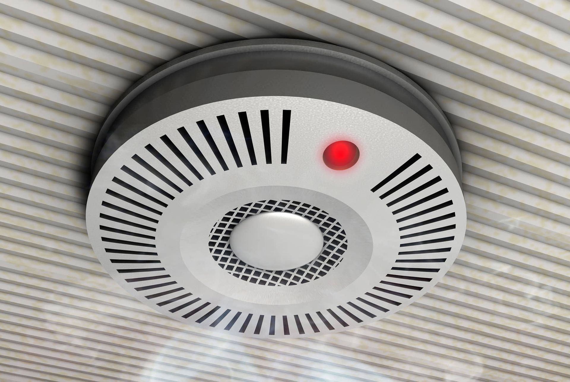 Detector de humo en el techo, con una luz roja iluminada.