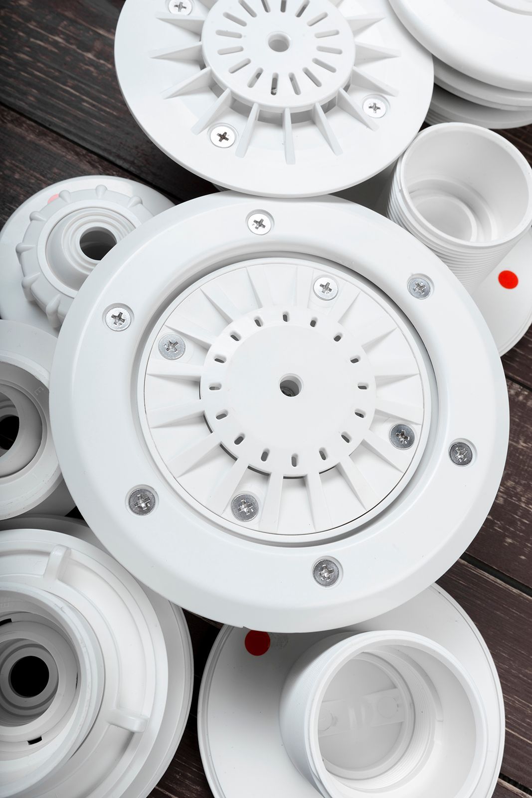 Cabezales de rociadores de plástico blanco y componentes relacionados sobre una superficie de madera oscura.