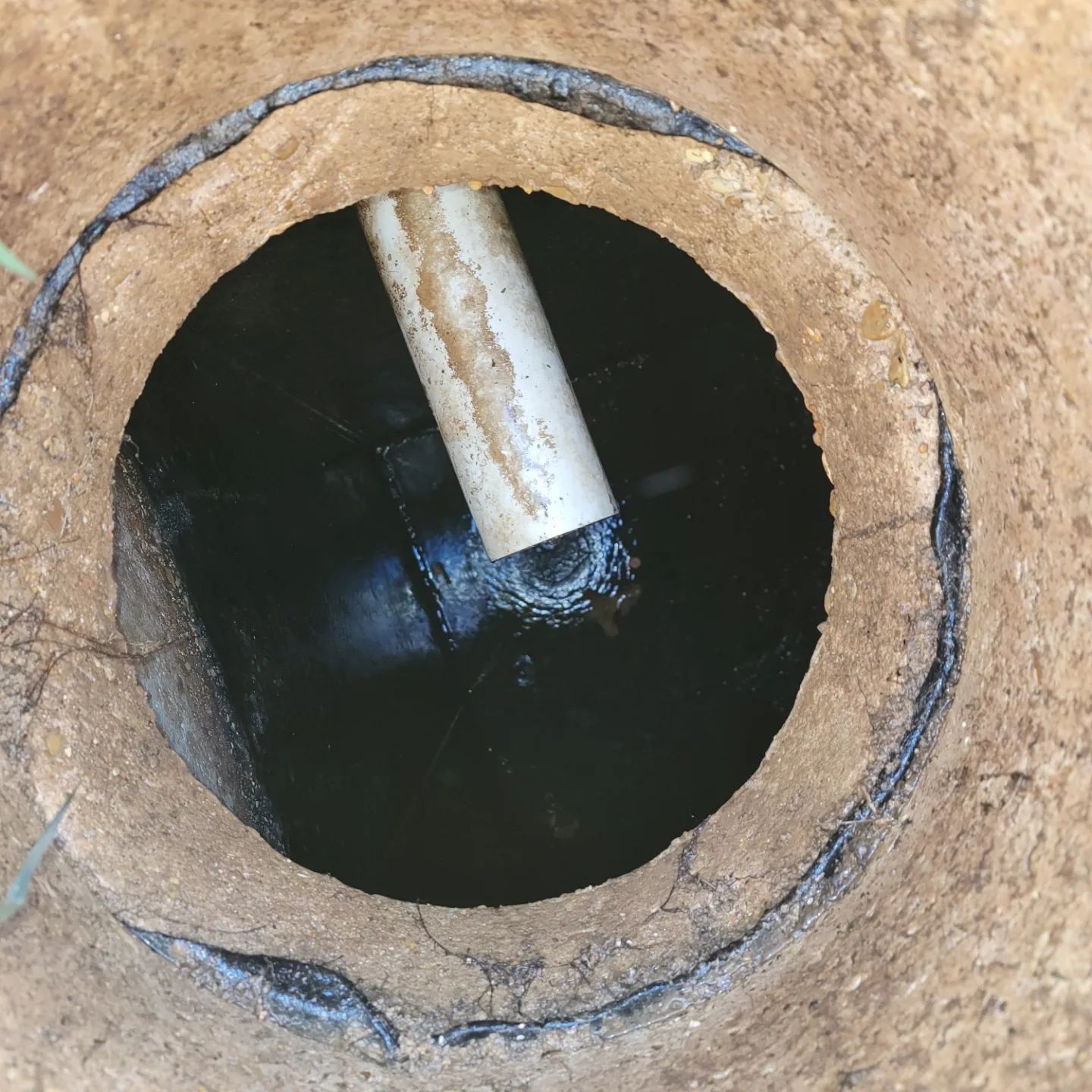 round well opening showing a water surface with a partially submerged rusty pipe