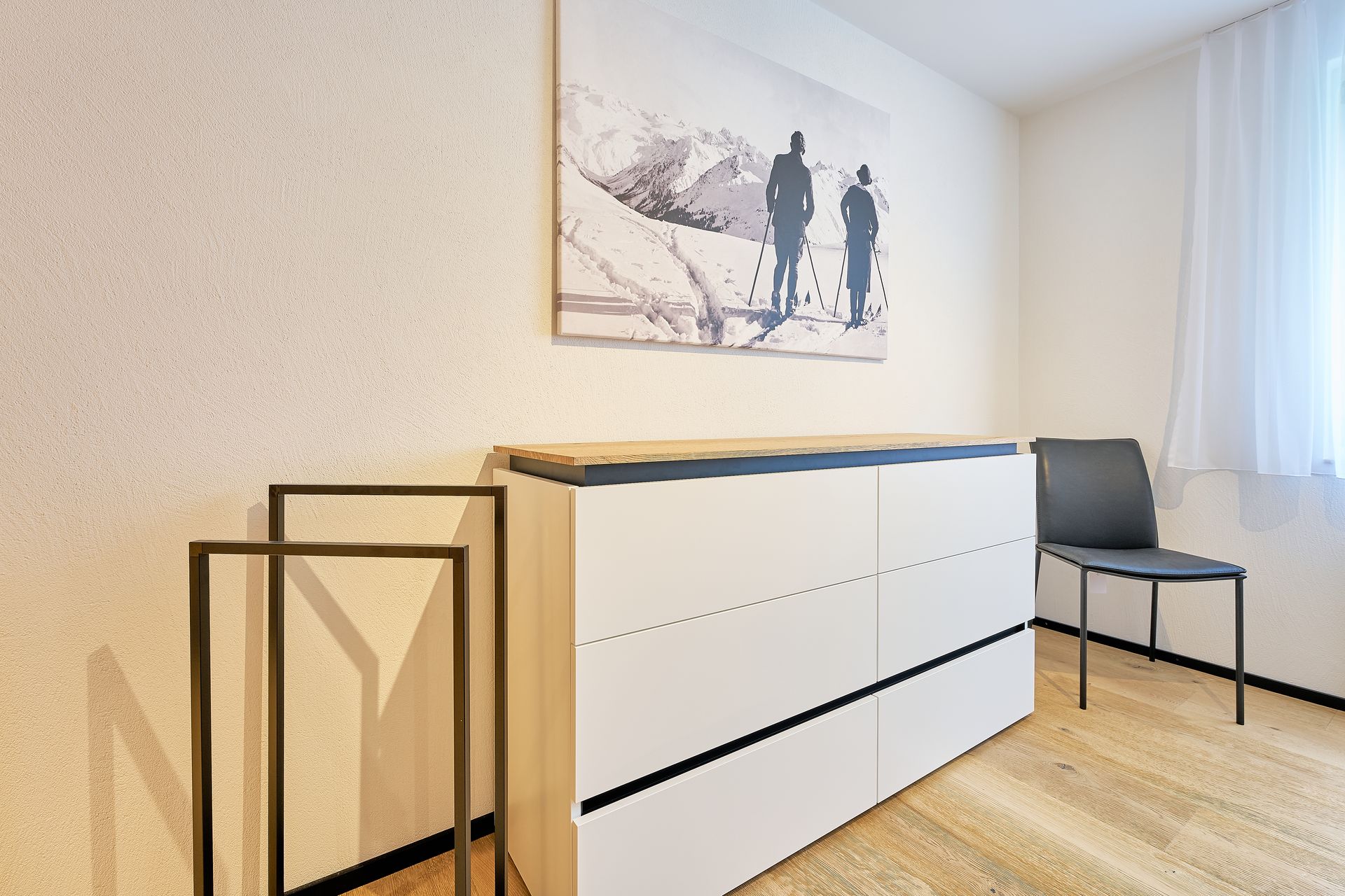 Ein Zimmer mit einer Kommode und einem Stuhl und einem Gemälde an der Wand