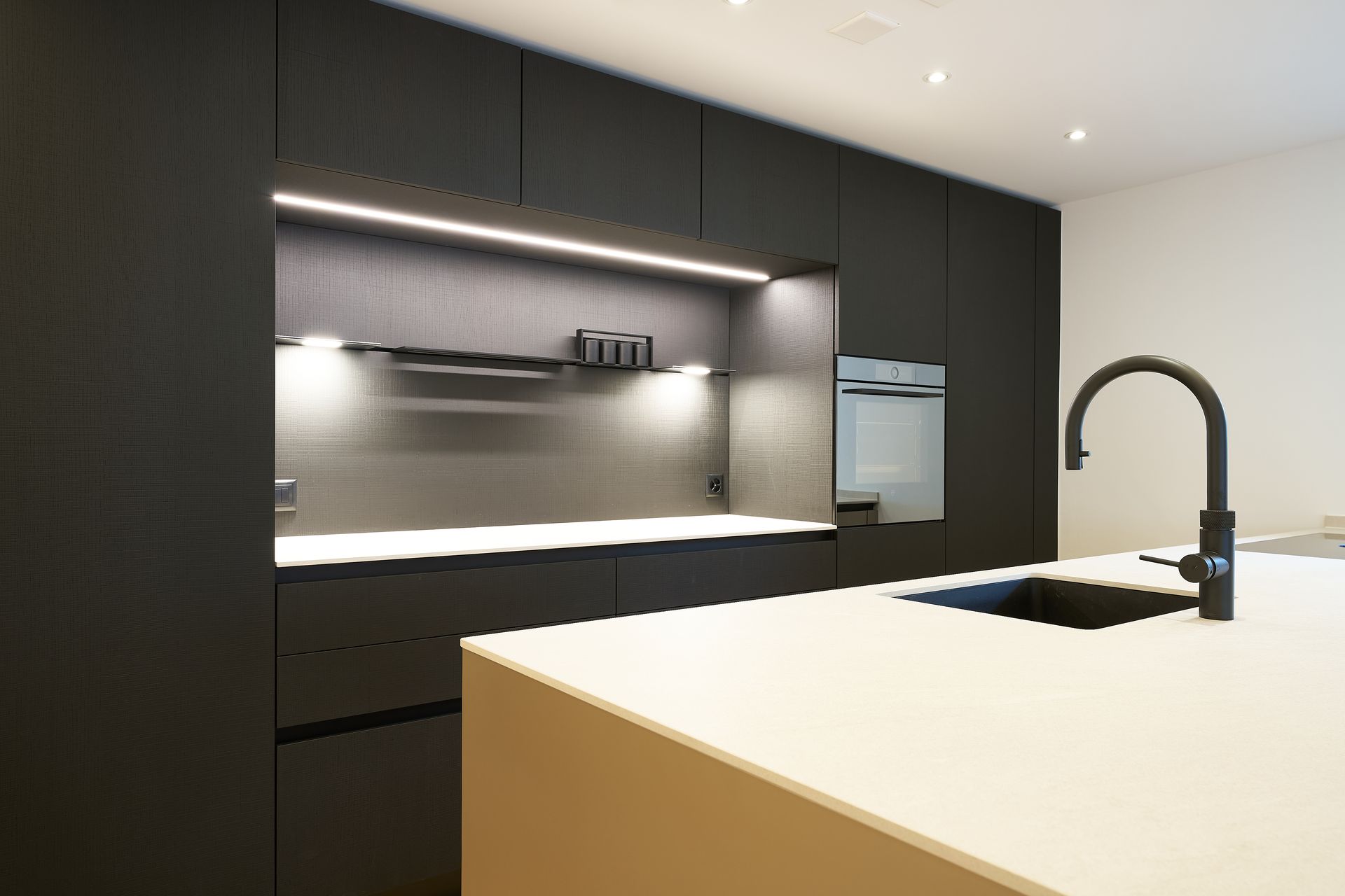 Eine Küche mit schwarzen Schränken und einer weißen Arbeitsplatte