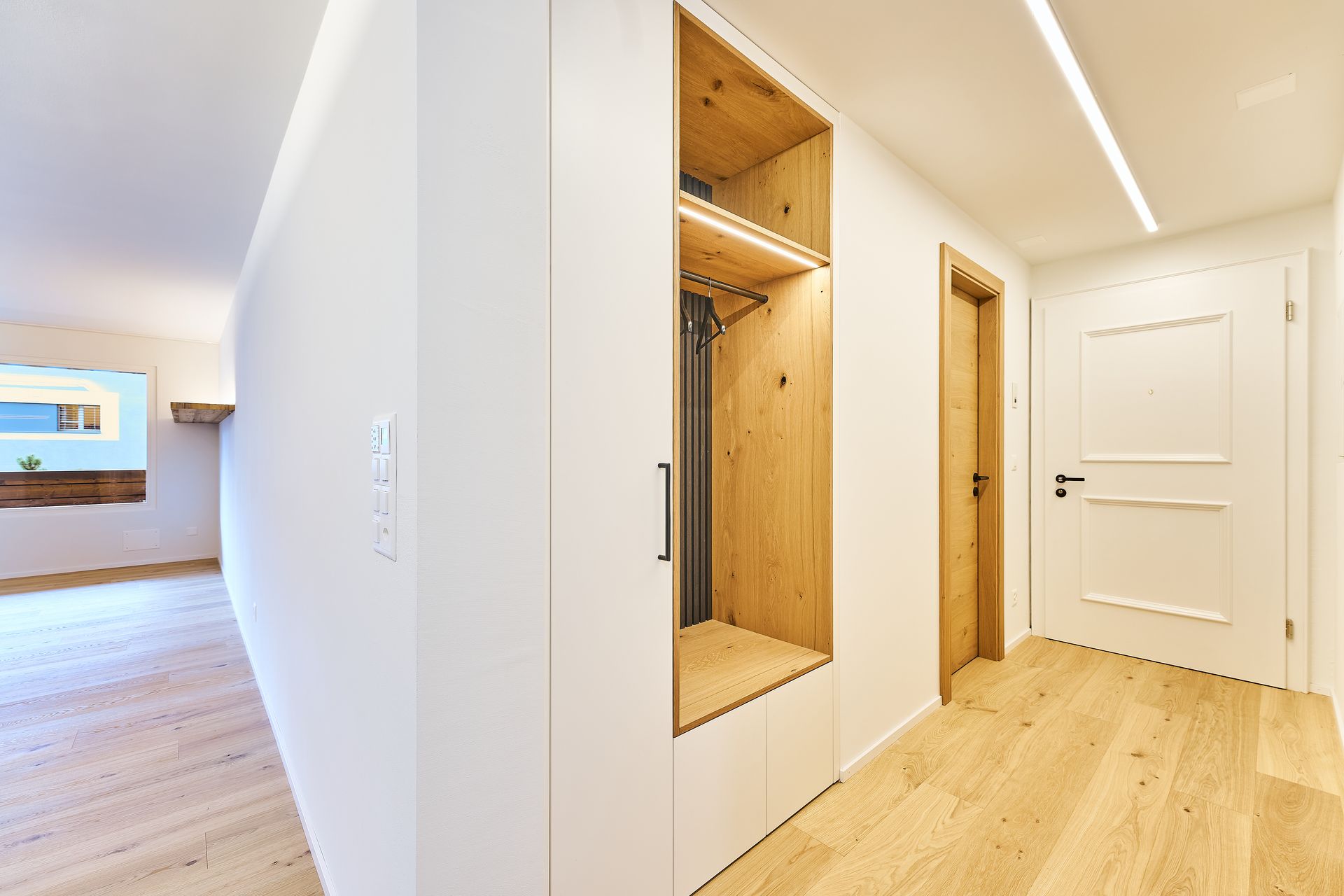 Ein Flur mit Holzboden und weißen Wänden