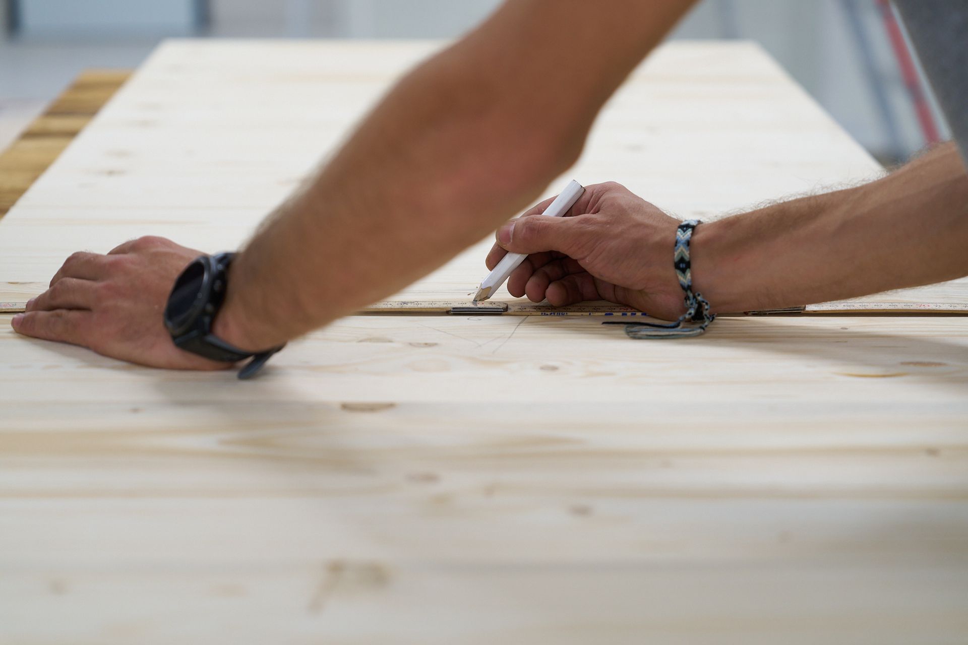 Ein Mann misst ein Stück Holz mit einem Lineal.