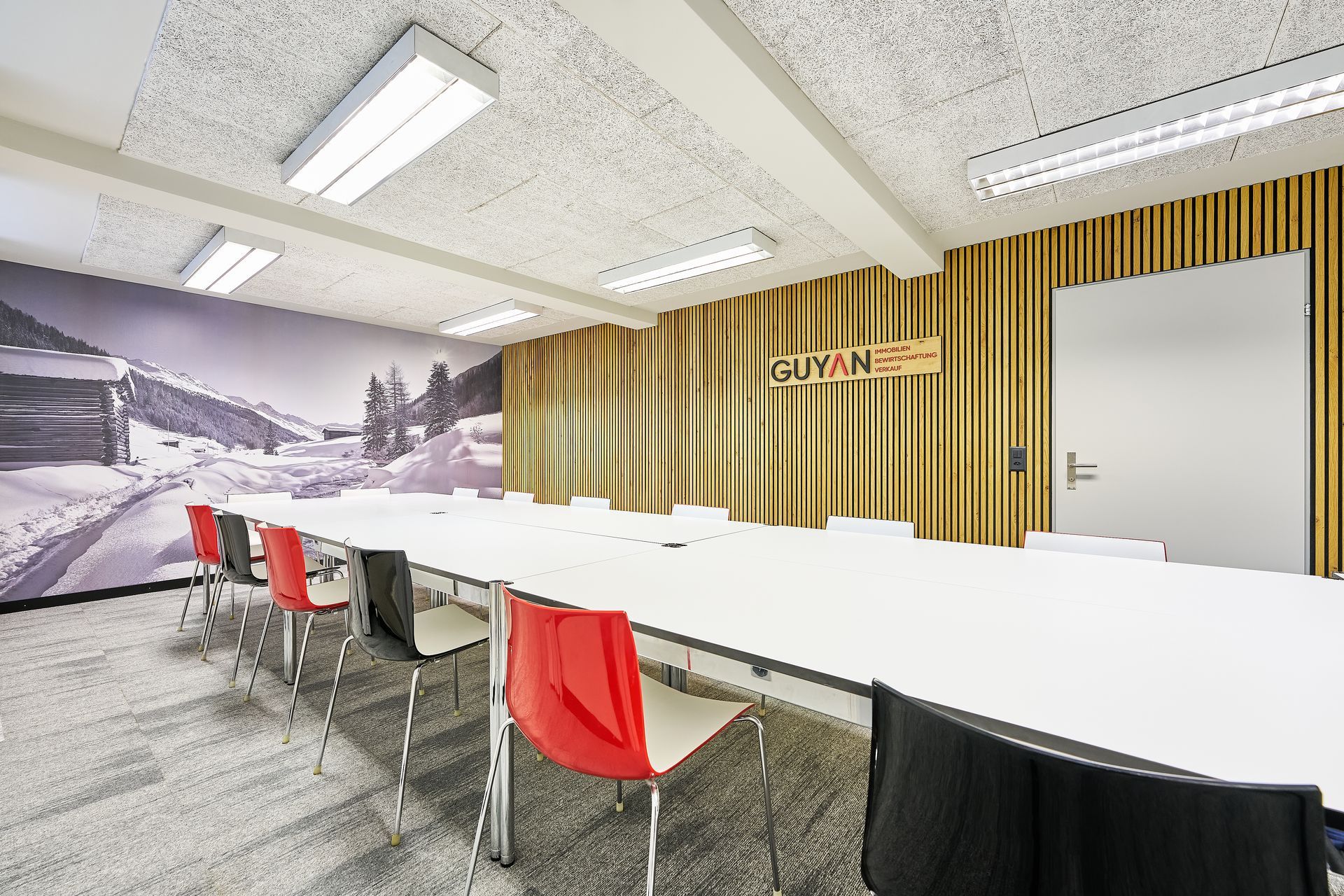 Ein Konferenzraum mit Tischen und Stühlen und einem Bild an der Wand.