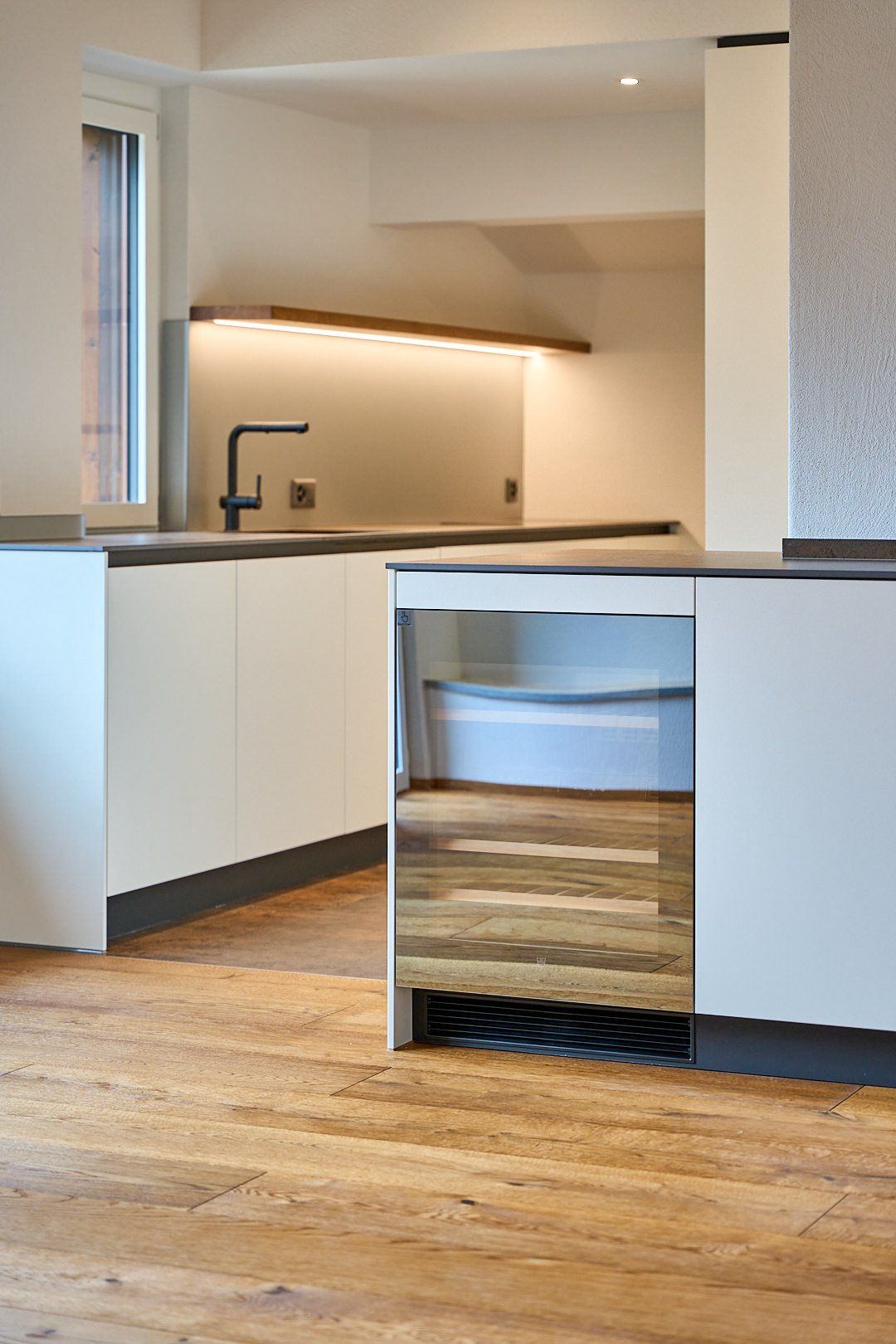 Eine Küche mit weißen Schränken und Holzböden und einer Spüle.