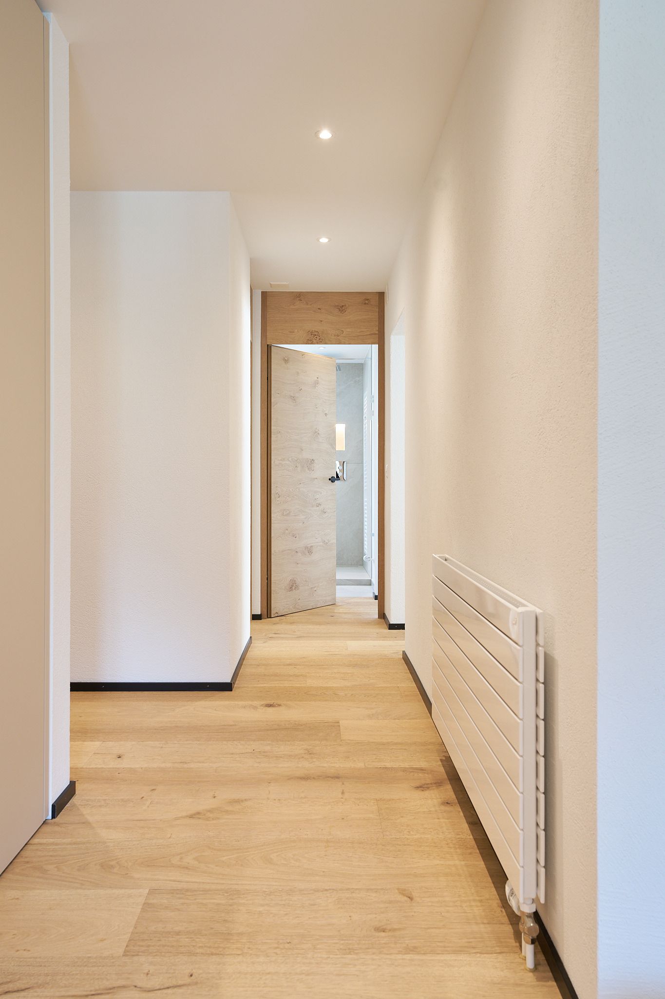 ein langer Flur mit Holzböden und einem weißen Heizkörper.
