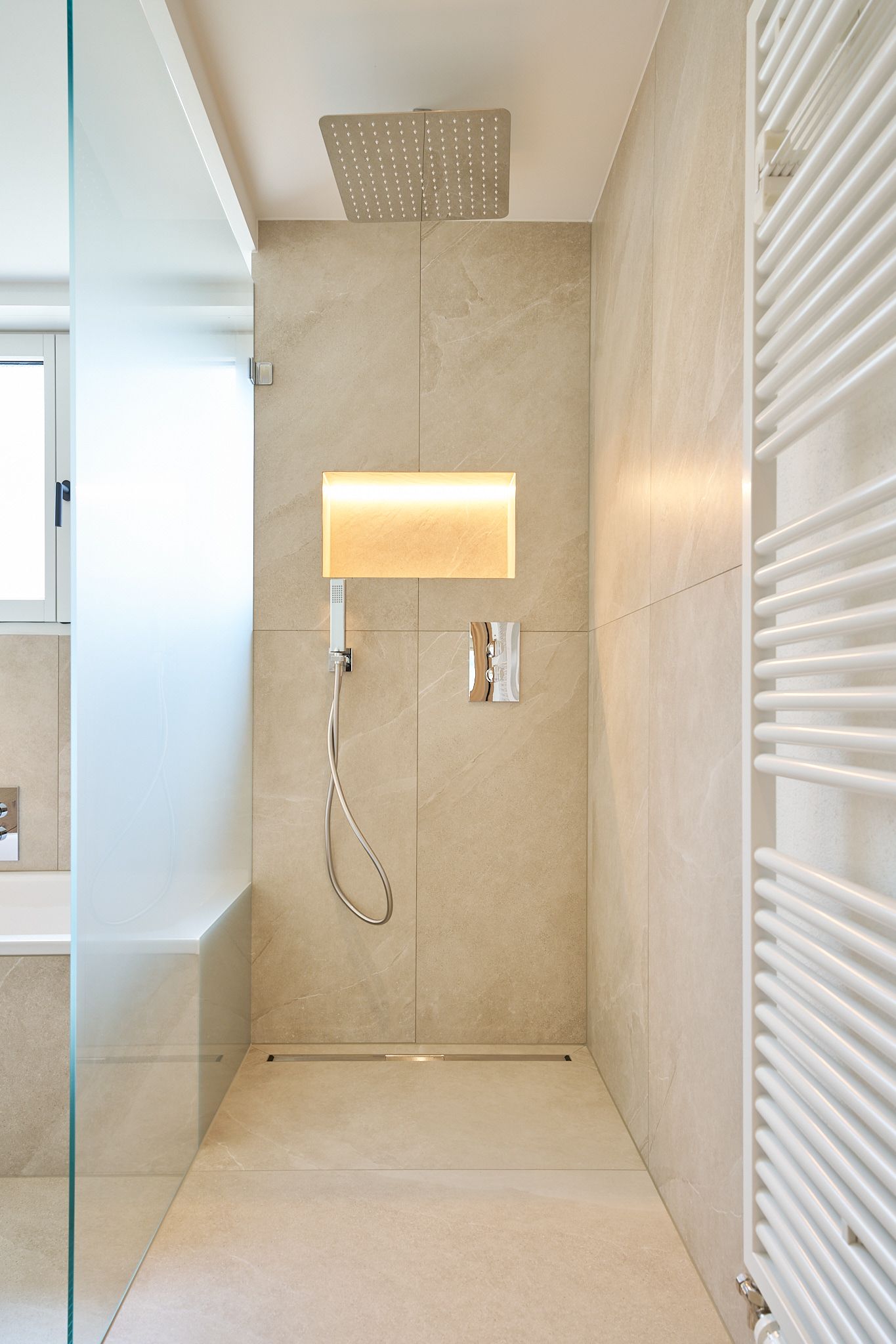 Ein Badezimmer mit ebenerdiger Dusche und Handtuchhalter.