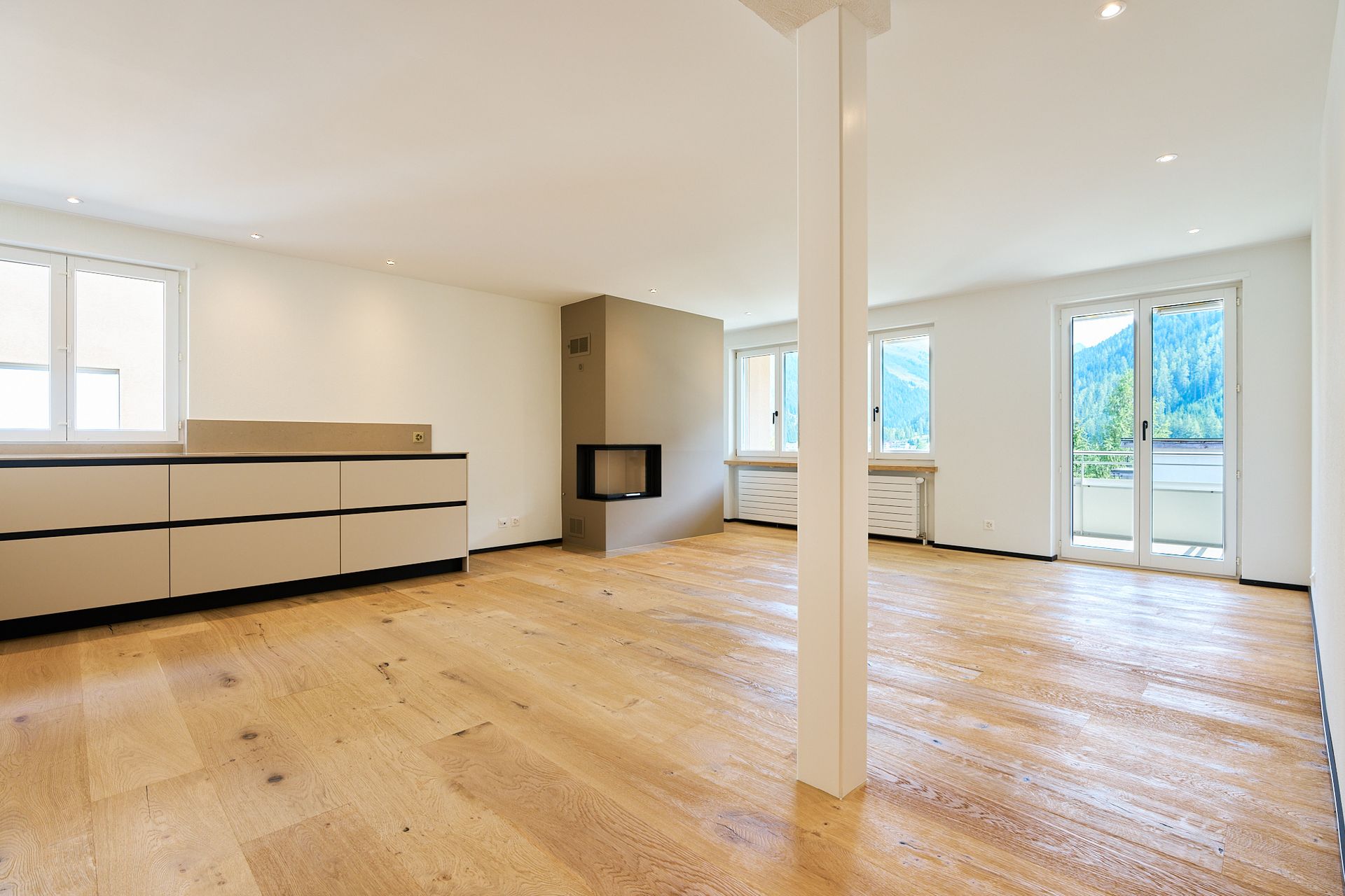 Ein leeres Wohnzimmer mit Hartholzböden und weißen Wänden