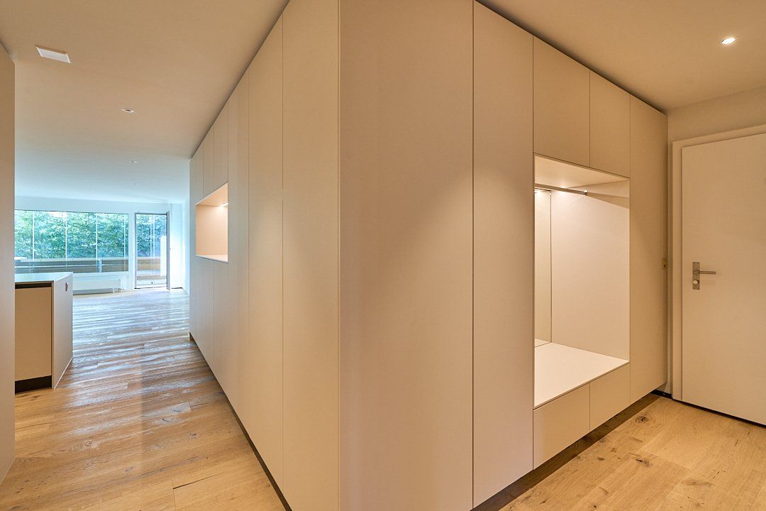 Ein Flur mit weißen Wänden und Holzböden, der zu einem Wohnzimmer führt.