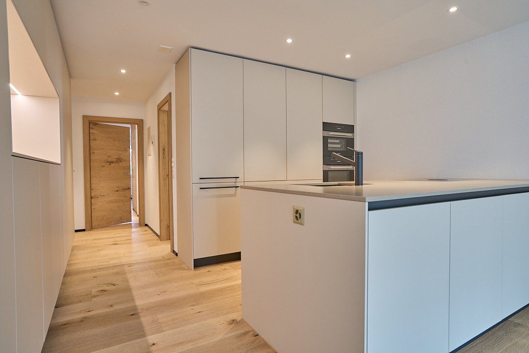 Eine Küche mit weißen Schränken und einem Holzboden