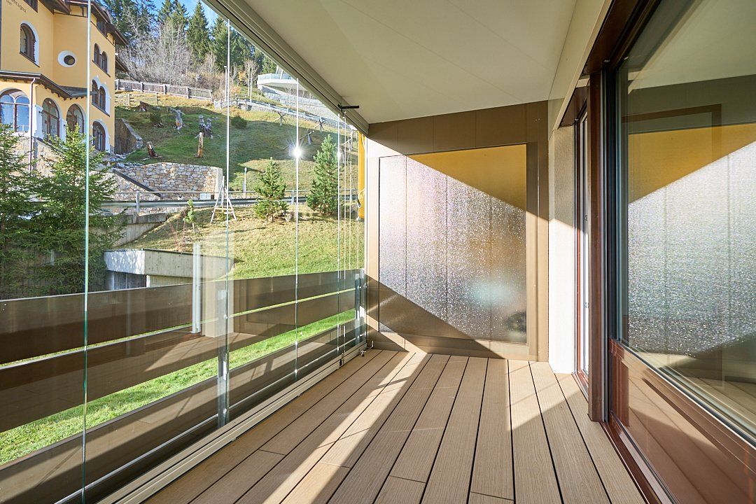 Ein Balkon mit Glasgeländer und Holzboden