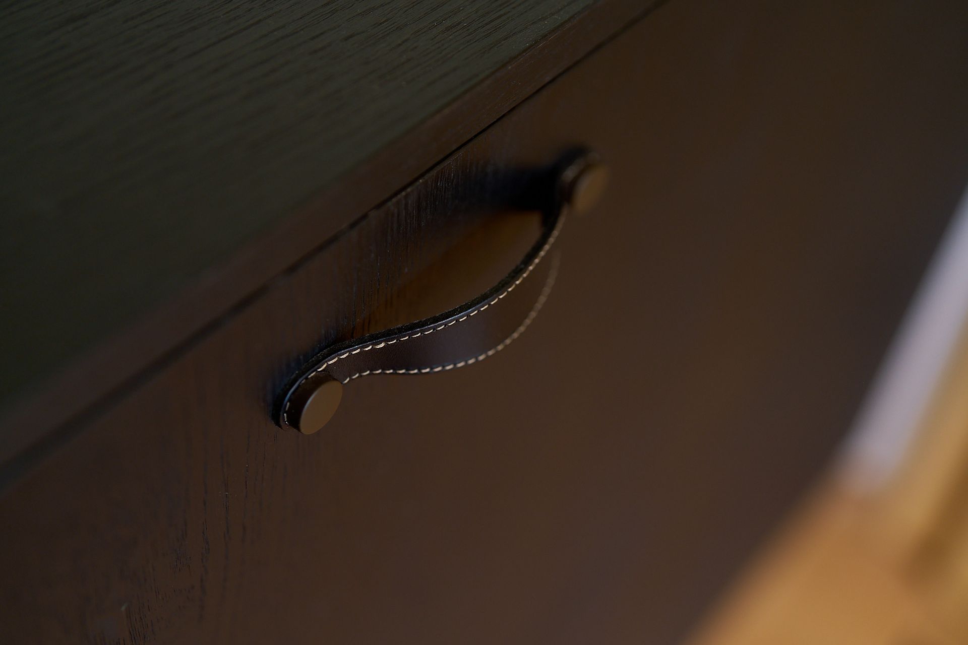 Eine Nahaufnahme eines schwarzen Schranks mit einem Ledergriff.