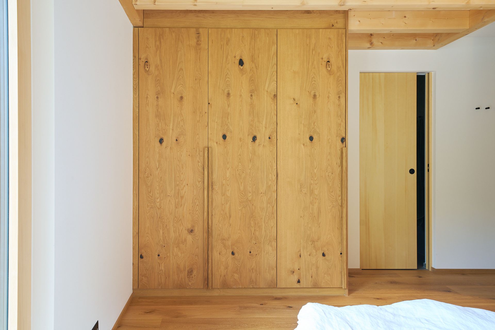 Ein Schlafzimmer mit einem Bett, Holzschränken und einer Holztür.