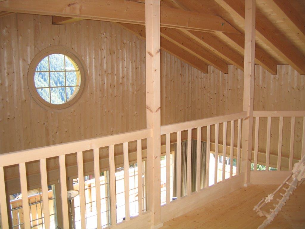 Ein Holzgebäude mit einem runden Fenster und einem Geländer