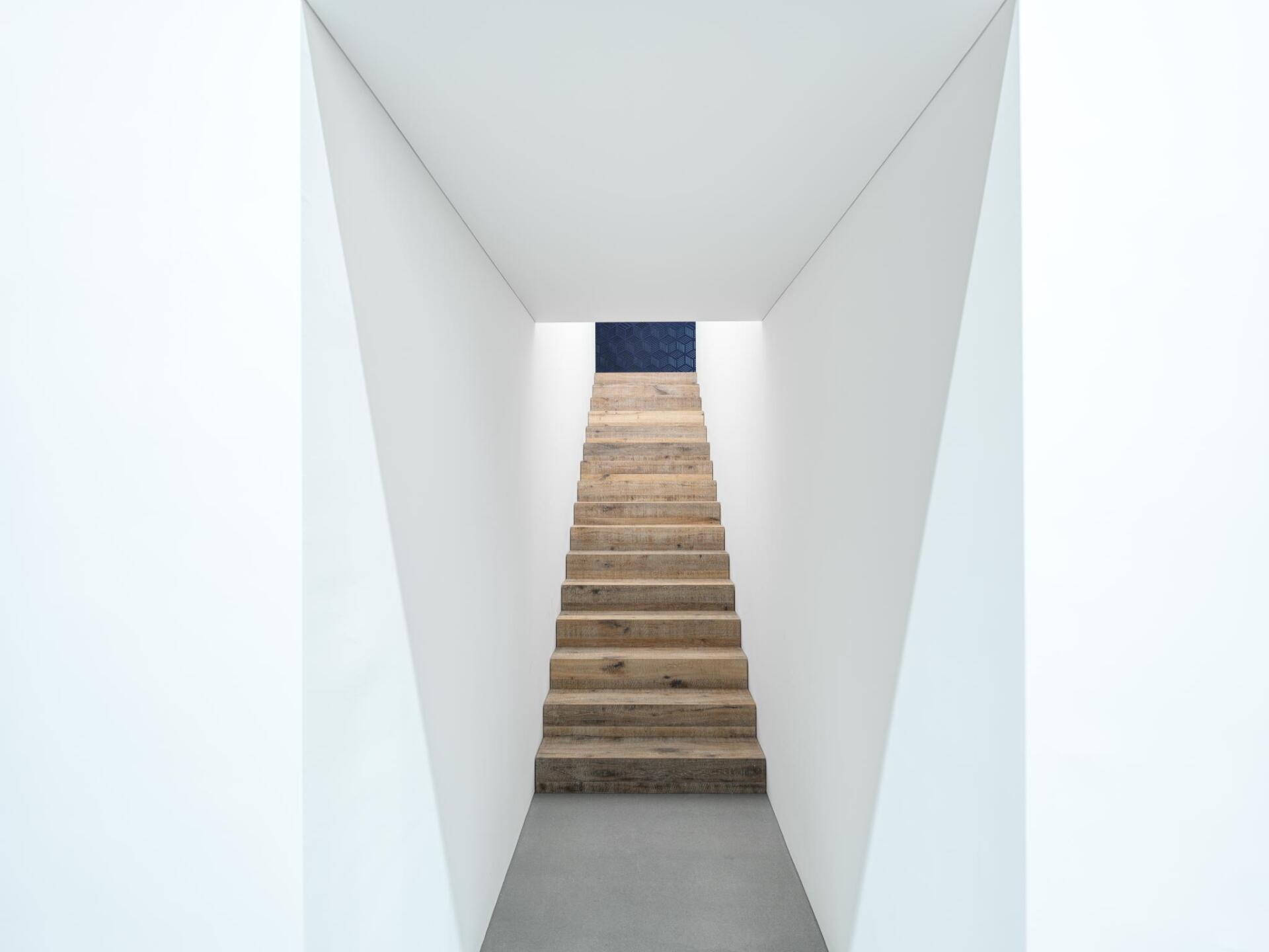 Ein Flur mit Holztreppe, die zu einer blauen Tür führt