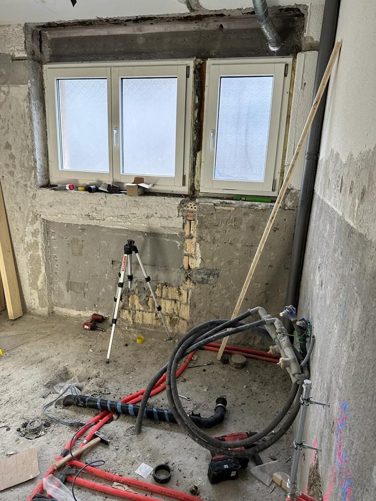 Ein Raum mit einem Fenster und vielen Rohren auf dem Boden.