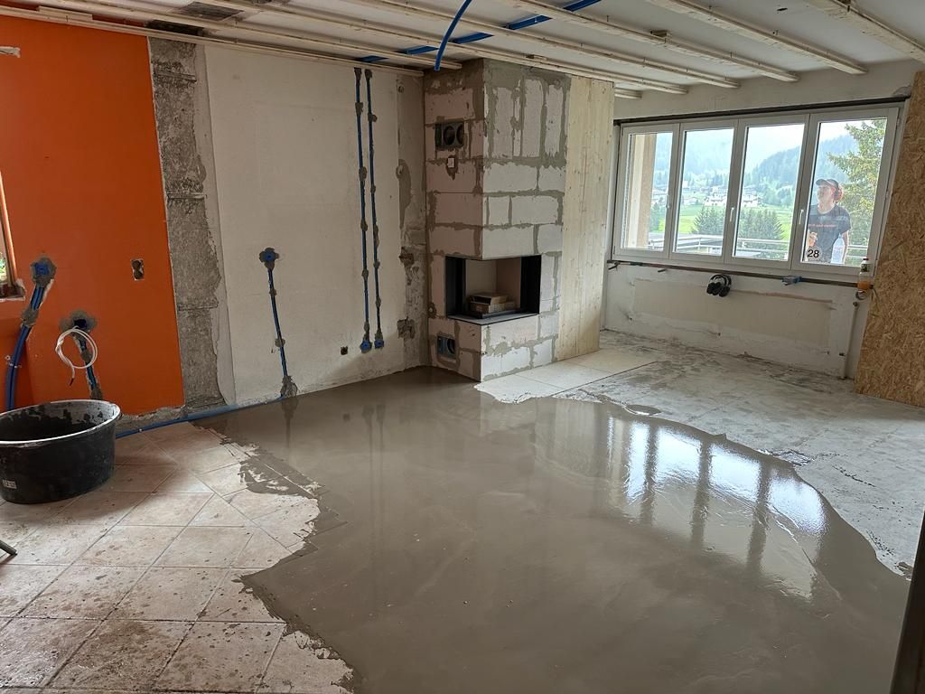 ein Wohnzimmer mit Kamin und einem Eimer Zement auf dem Boden.