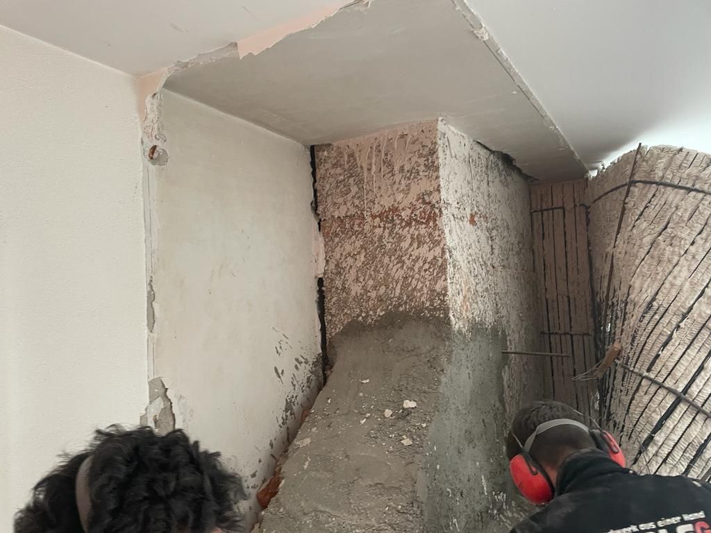 Ein Mann mit Ohrenschützern arbeitet an einer Wand.