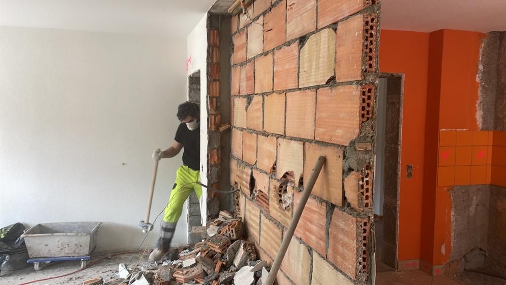 Ein Mann arbeitet an einer Ziegelwand in einem Raum.