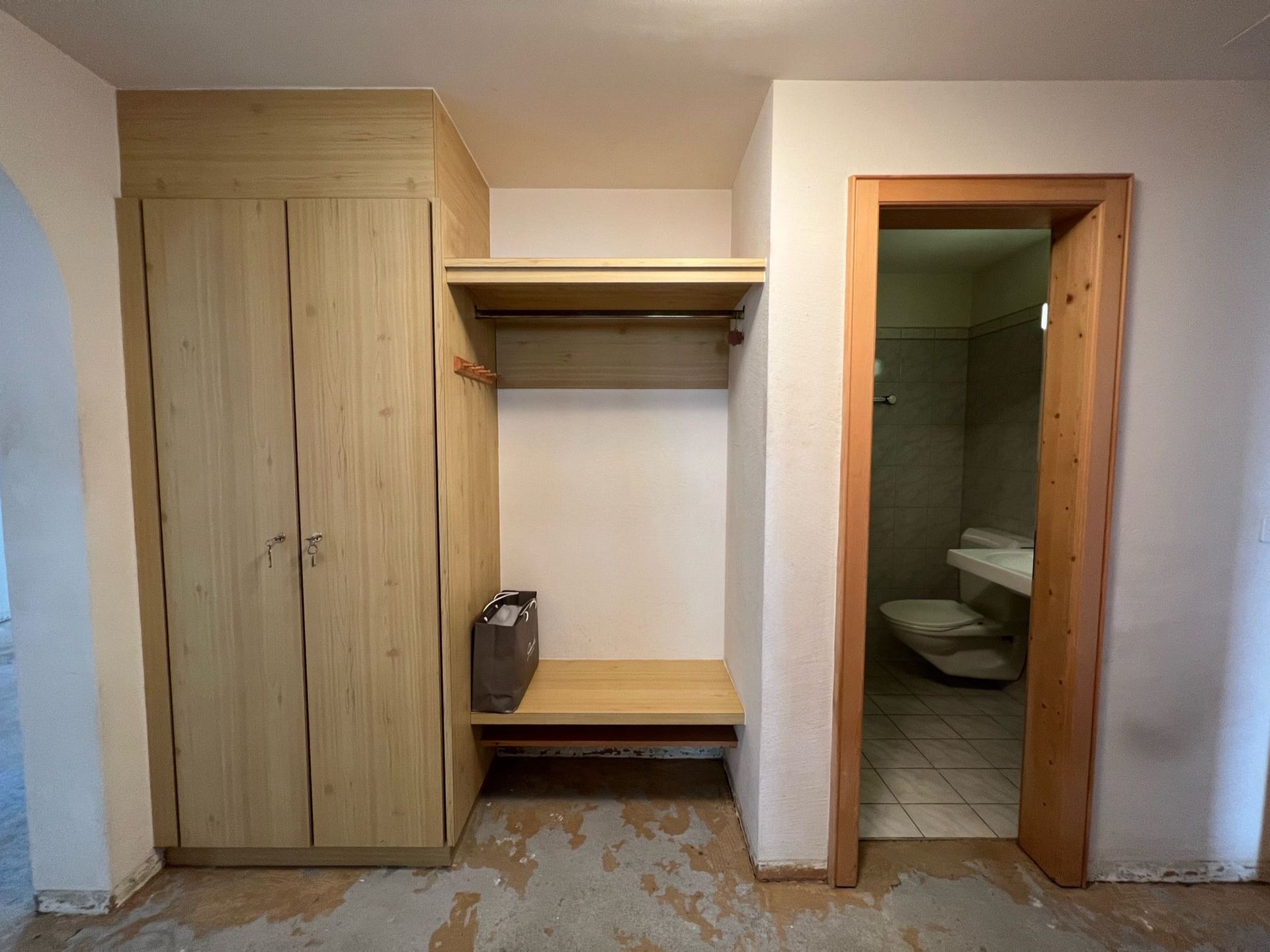 Ein Zimmer mit einem Schrank und einer Tür, die zu einem Badezimmer führt