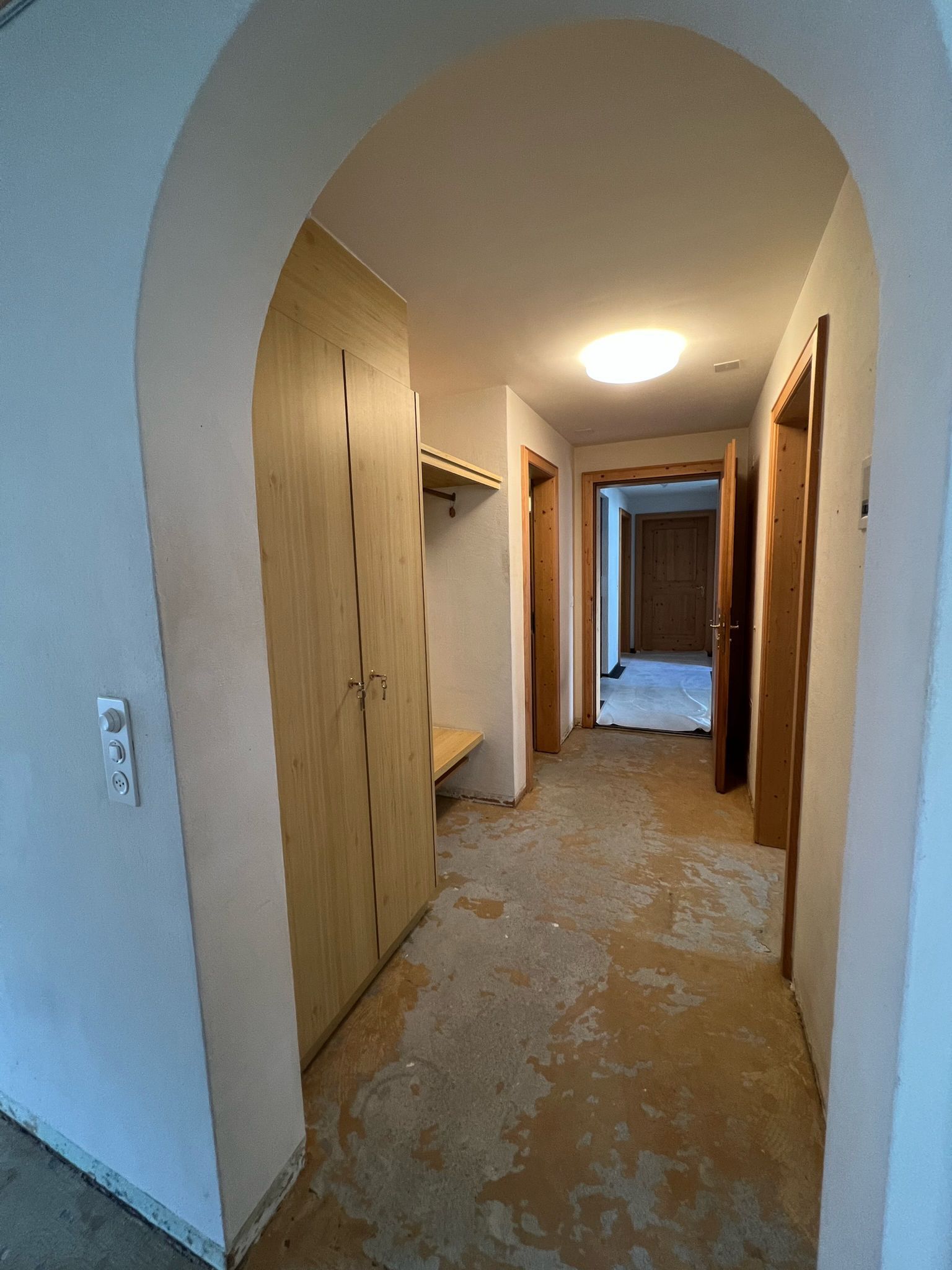 Ein langer Flur mit einem hölzernen Torbogen, der zu einem Zimmer führt.