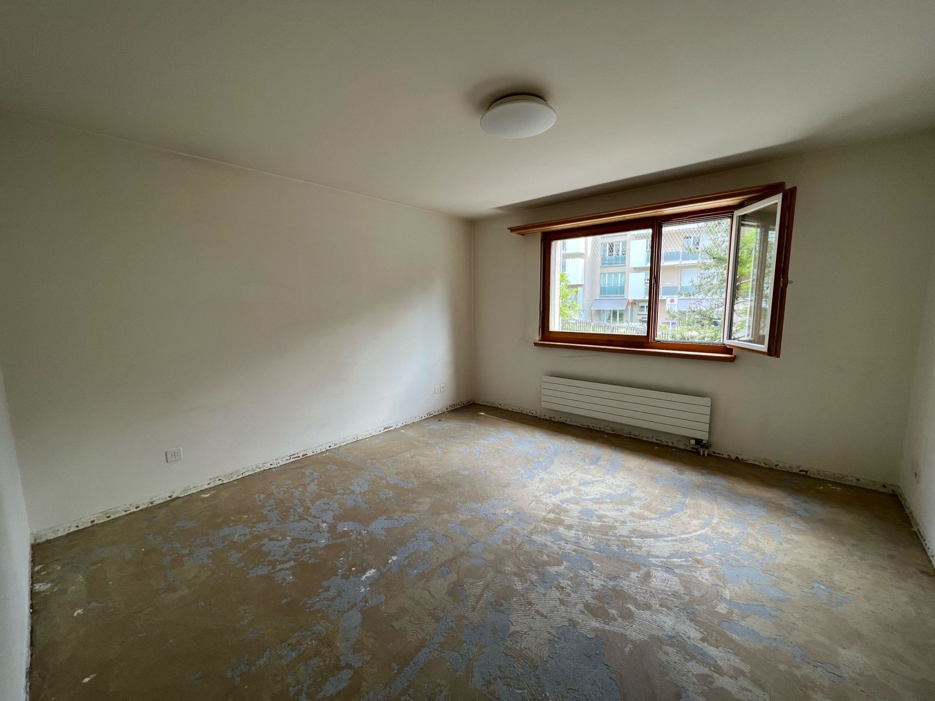 Ein leerer Raum mit einem Fenster und einem Heizkörper.