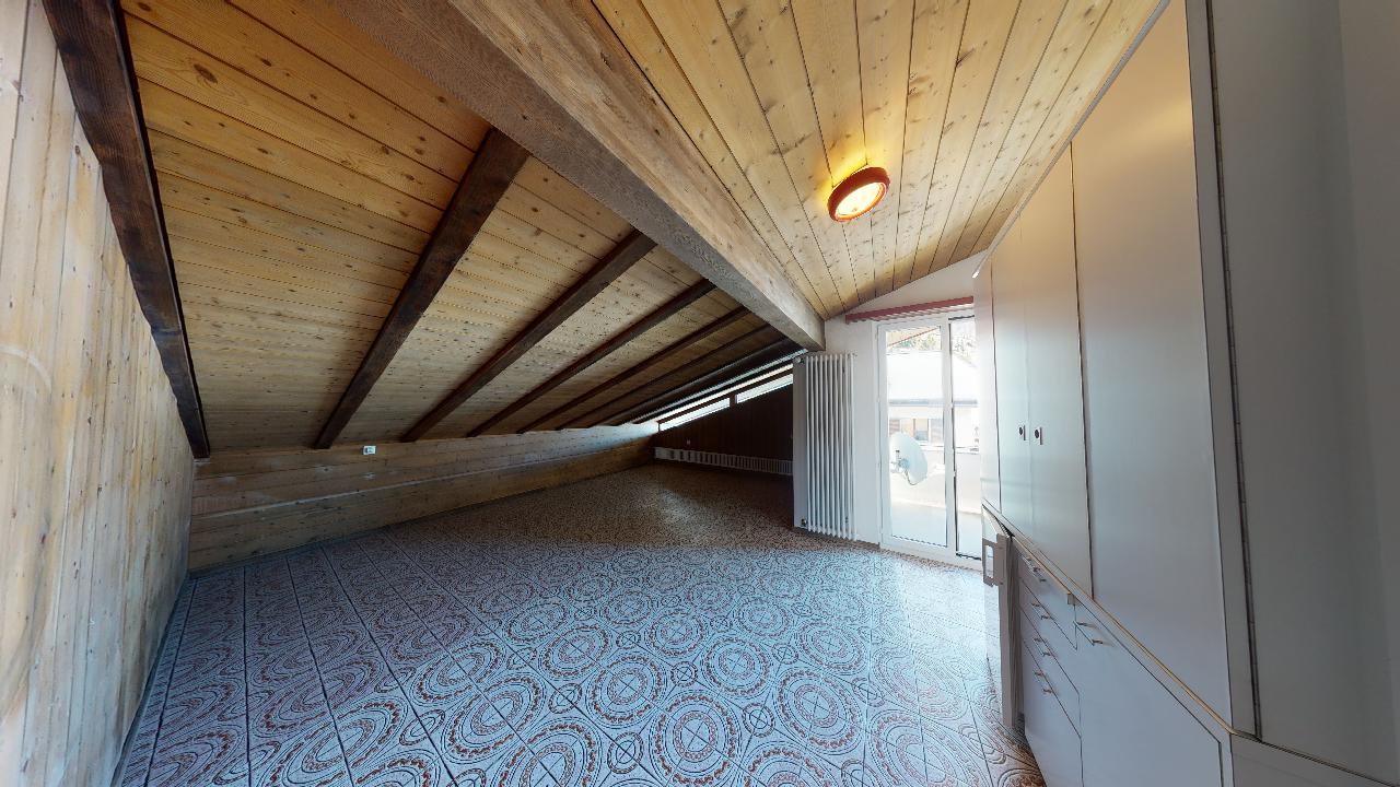 Ein sehr langer Flur mit Holzdecke und Mosaikboden.