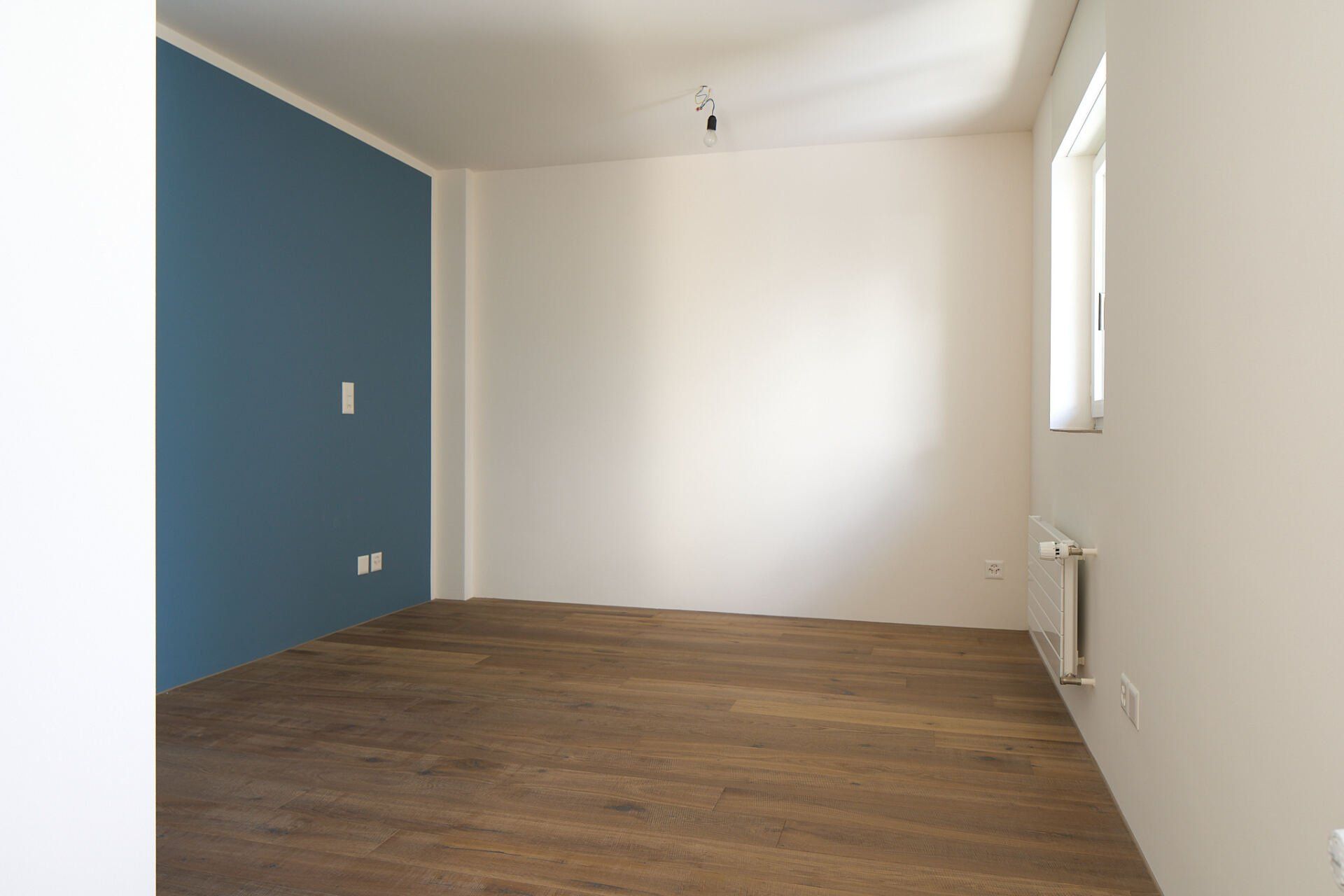 Ein leerer Raum mit einer blauen Wand und einem Fenster