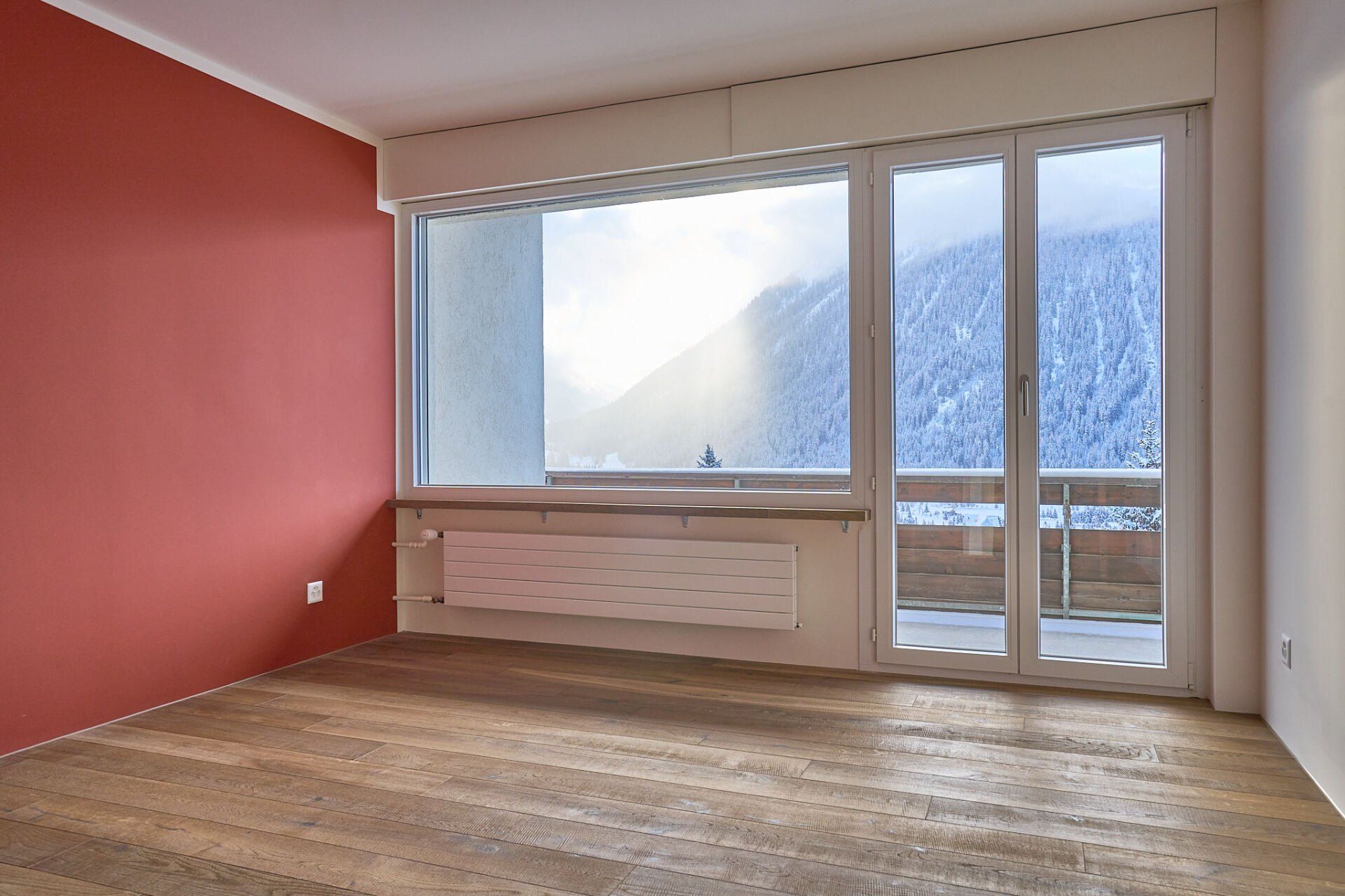 Ein leerer Raum mit roten Wänden und einem großen Fenster