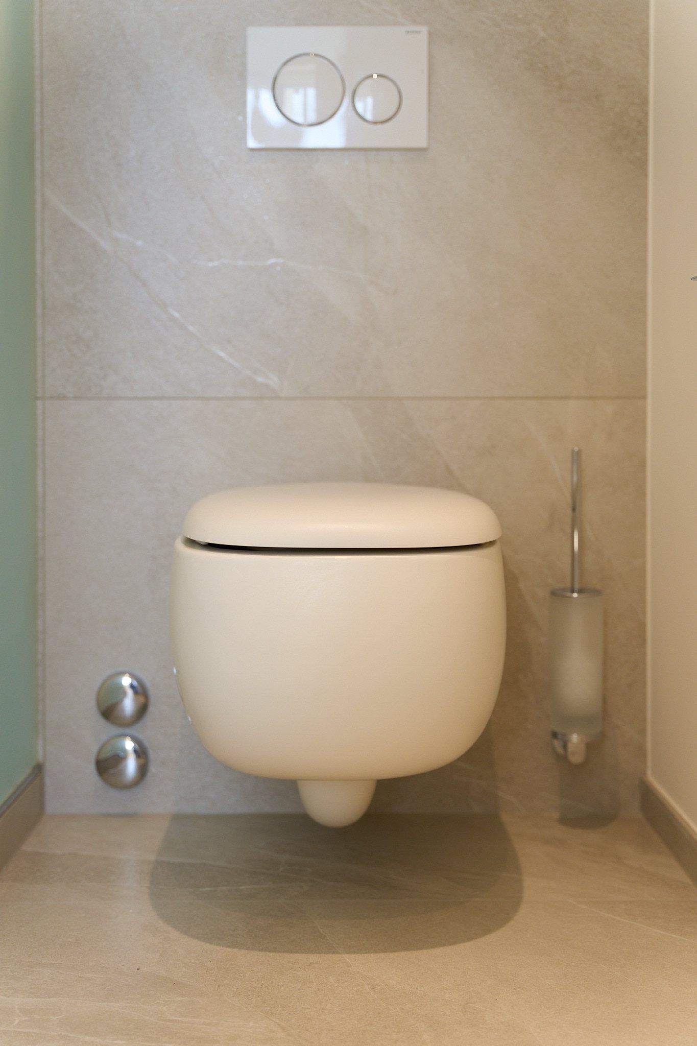 In einem Badezimmer hängt eine weiße Toilette an der Wand.