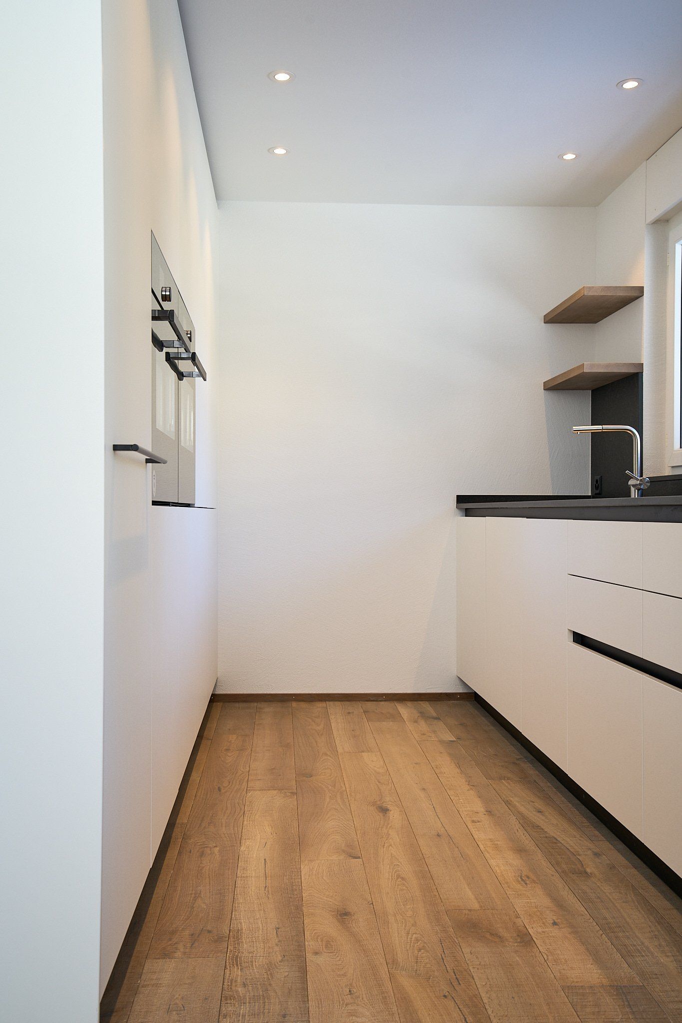 Eine Küche mit weißen Schränken und Holzböden