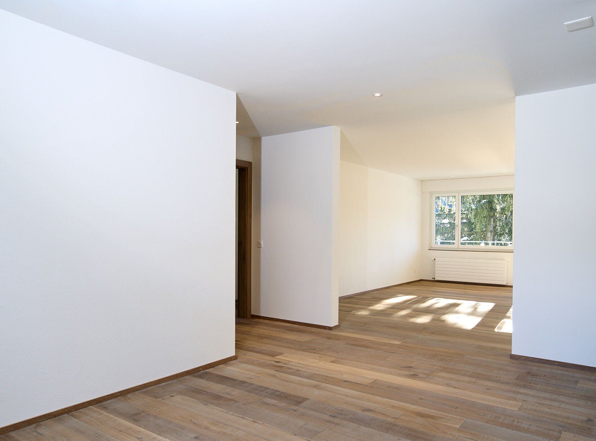 Ein leerer Raum mit weißen Wänden und Holzböden