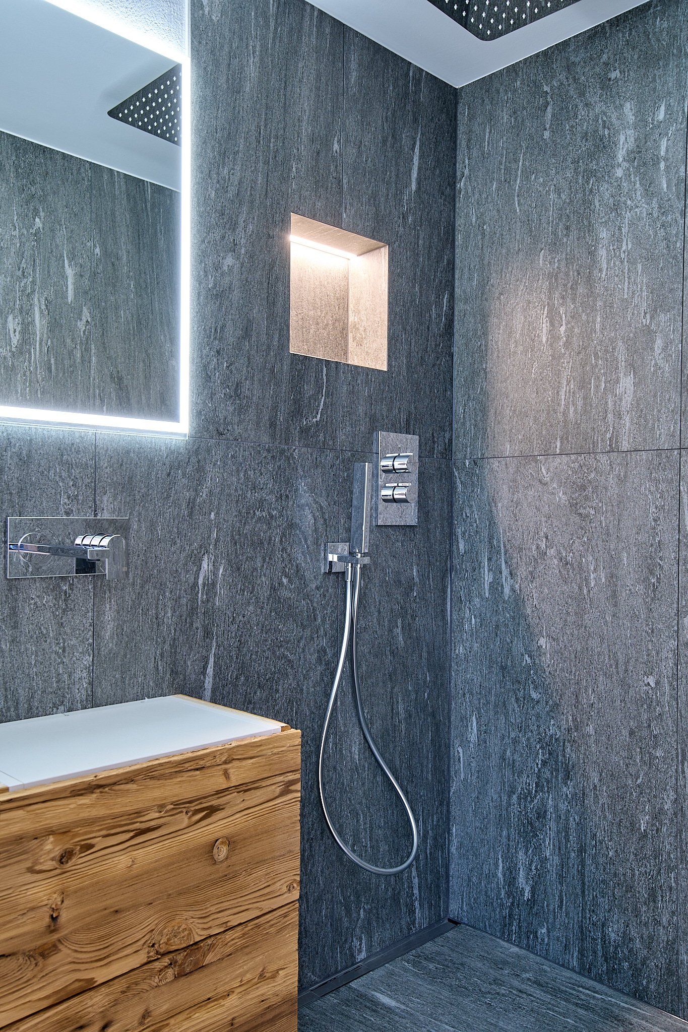 Ein Badezimmer mit ebenerdiger Dusche, Waschbecken und Spiegel.