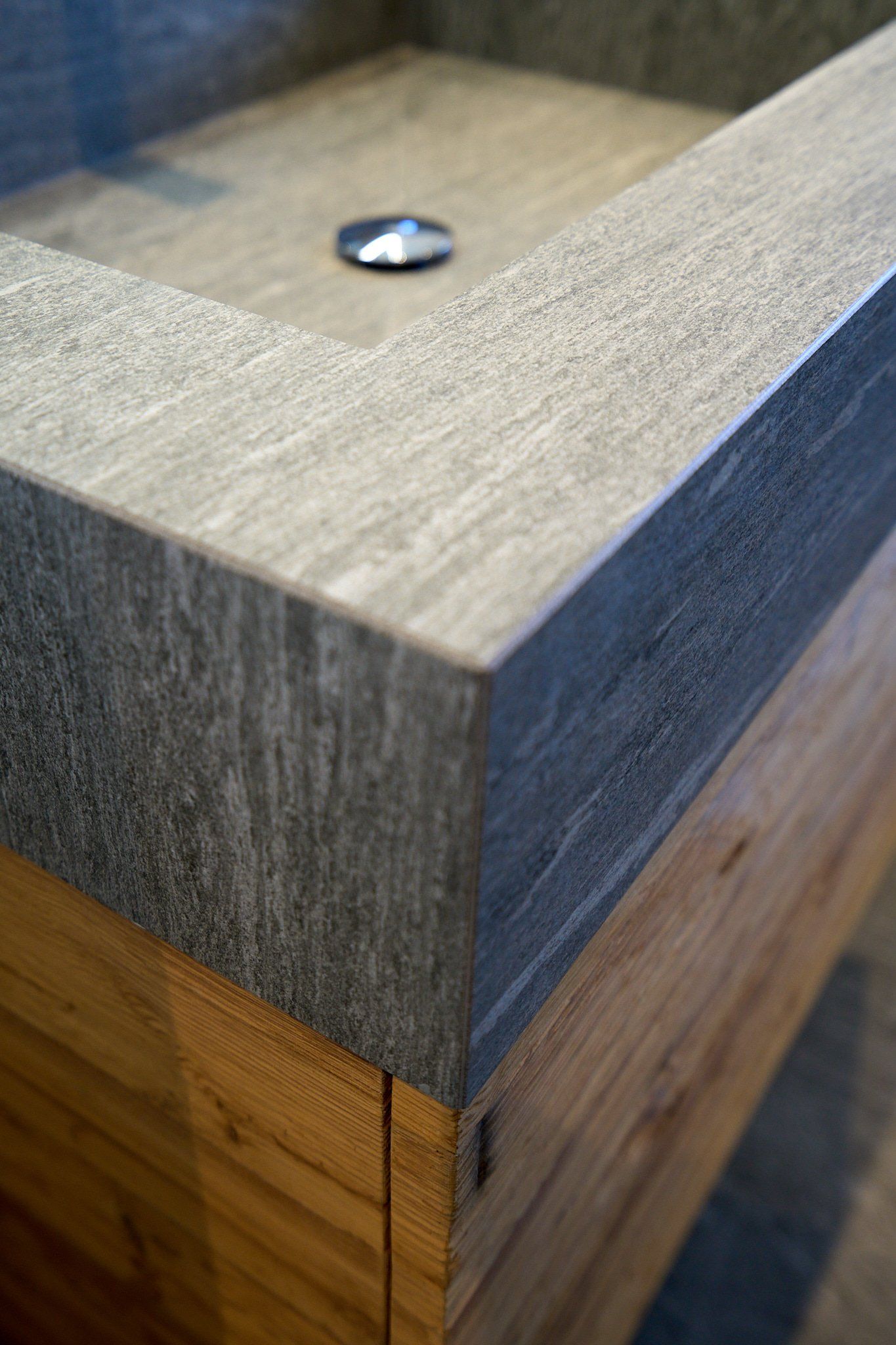 Ein Badezimmerwaschbecken mit Holzplatte und Abfluss.