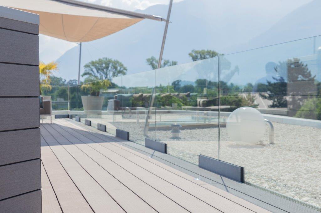 Ein Balkon mit Glasgeländer und Holzterrasse