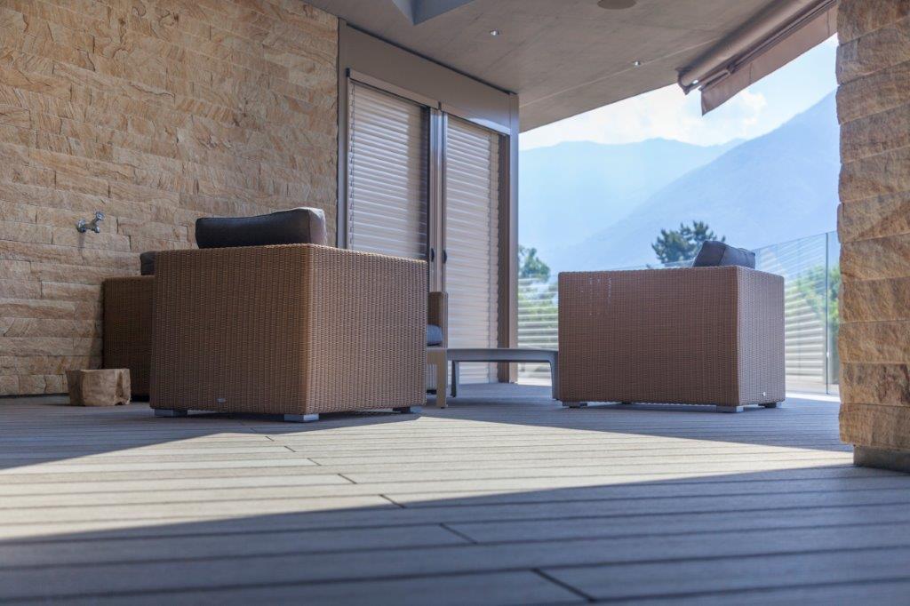 Eine Terrasse mit Stühlen und einem Tisch mit Bergen im Hintergrund