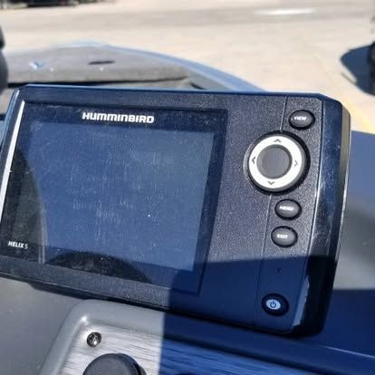 A hummingbird gps is sitting on the dashboard of a boat.