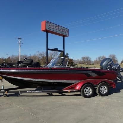 A red fishing boat is parked in front of a sign that says great lakes