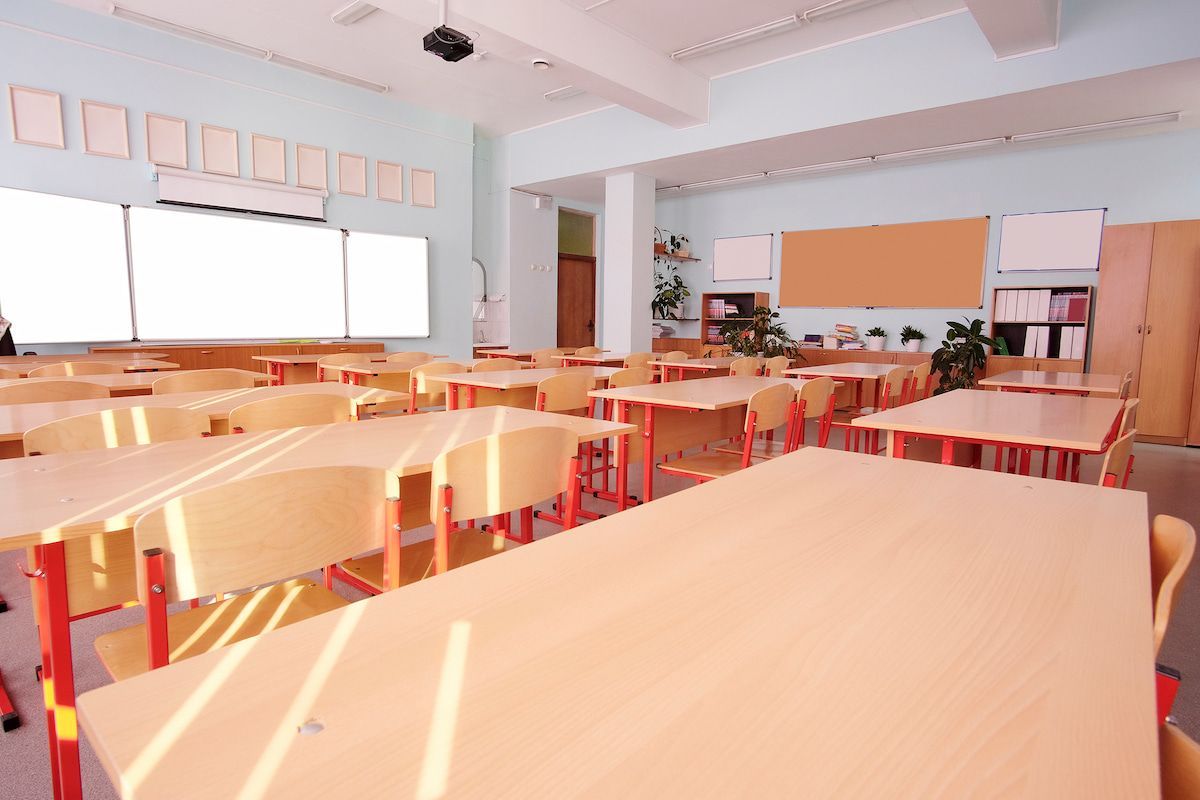An Empty Classroom With Tables and Chairs and a Blackboard — Ocean Grove Removals In Whittington, VIC