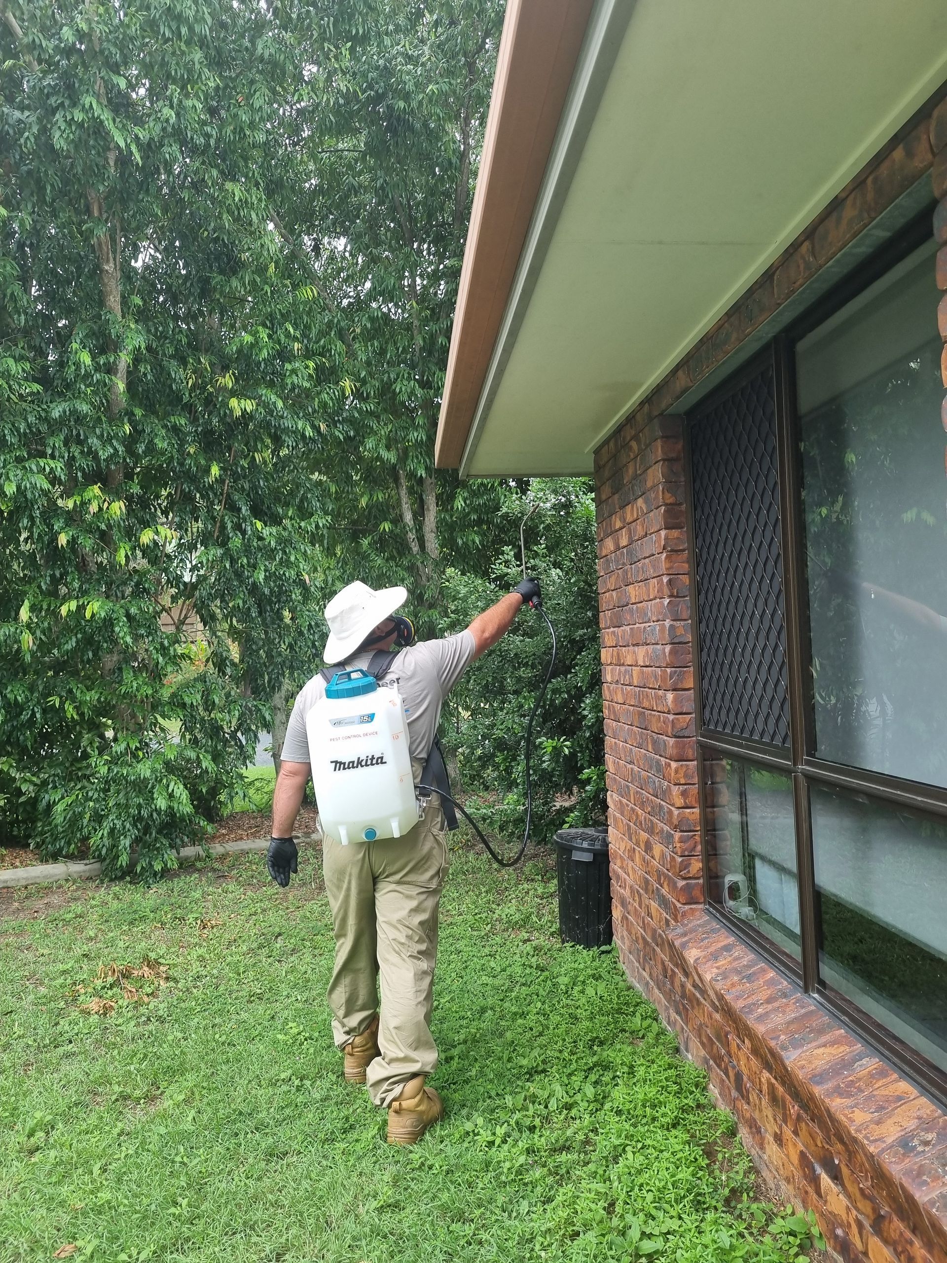 A Man in a Protective Suit is Spraying Chemicals in a Warehouse — Pioneer Pest Mackay In Glenella, QLD
