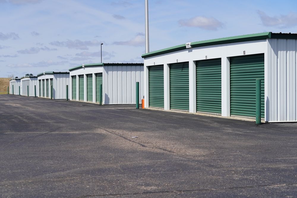 A Row of Storage Units With Green Doors Are Lined Up in a Parking Lot — Pioneer Pest Mackay In Glenella, QLD