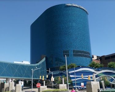 Blue-tiled Helen DeVos Children's Hospital building under a clear sky. A walkway and art are in the foreground.