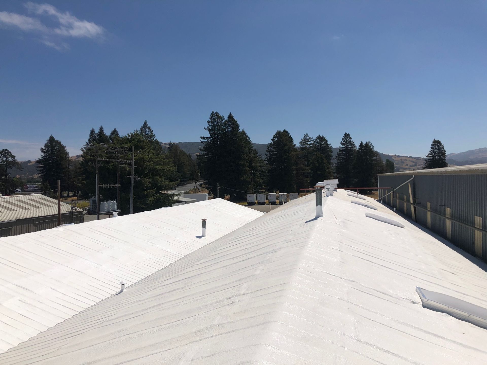 A man is rolling a roll of asphalt on a roof.